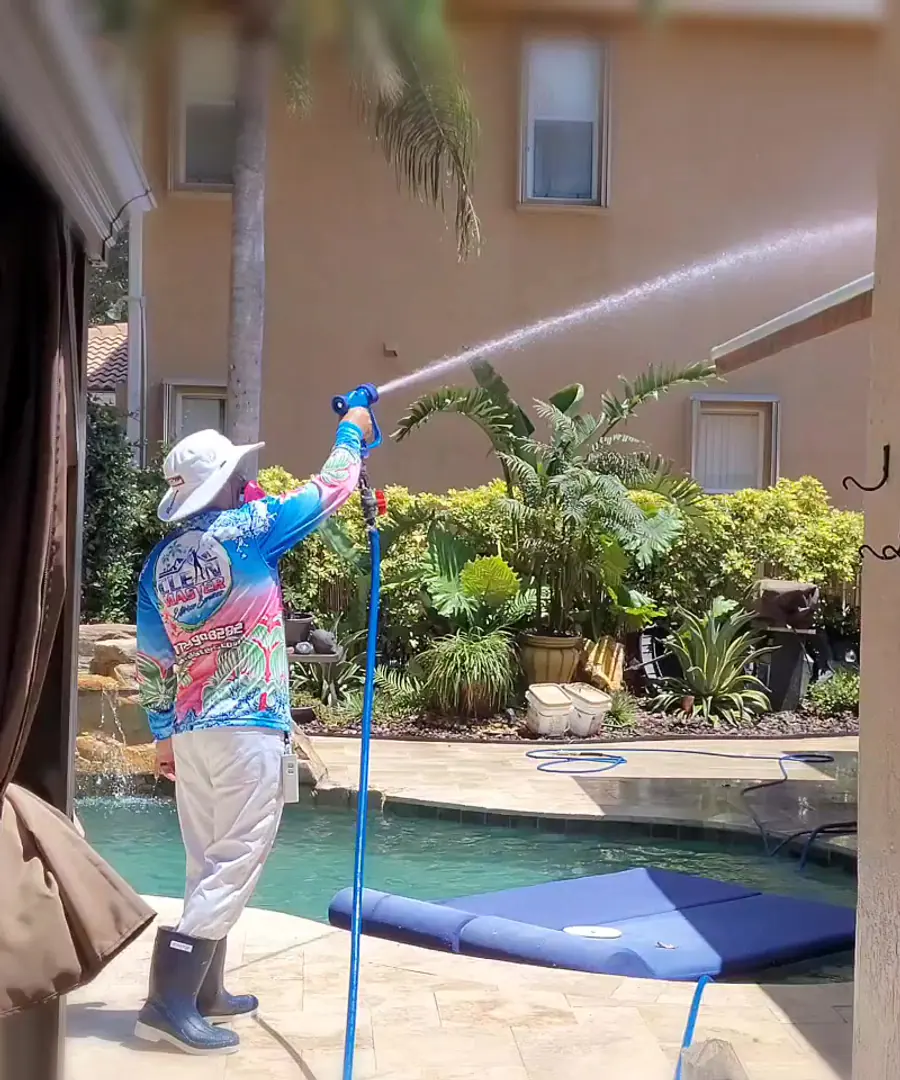 Clean Master technician washing a stucco exterior beside a screened pool area