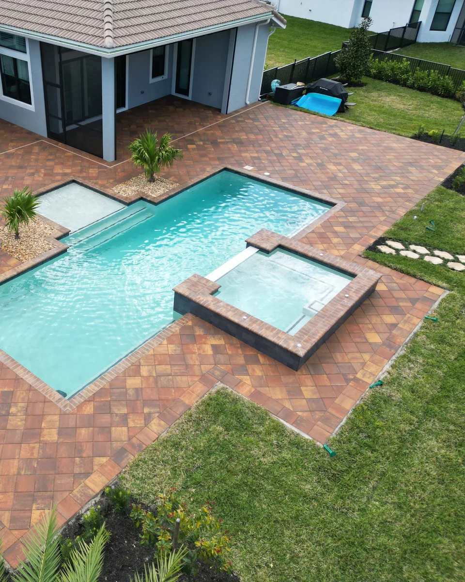 Paver pool deck surrounding an angular pool and raised spa