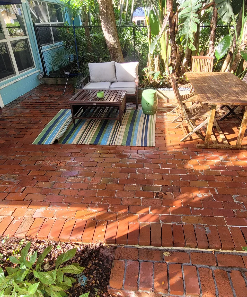 Brick patio beside a home with furniture and tropical planting