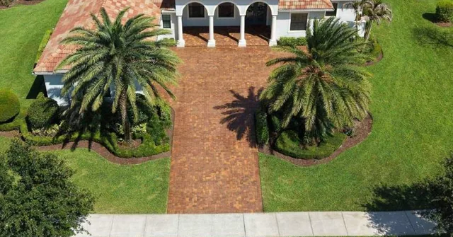 Paver driveway and palms in front of a white home